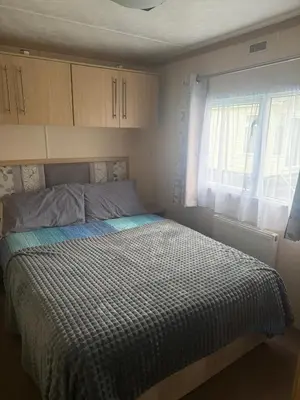 a bedroom with a bed with a checkered blanket at 6 Bed Static Carvan Seawick Holiday Park in Saint Osyth
