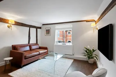 a living room with a leather couch and a glass table at Beautiful period property in historic town in Braintree