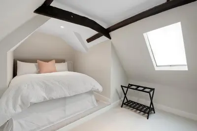 a white bedroom with a bed and a window at Beautiful period property in historic town in Braintree