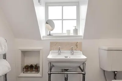 a white bathroom with a sink and a mirror at Beautiful period property in historic town in Braintree
