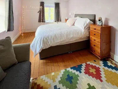 a bedroom with a bed with a dresser and a rug at Sandy Toes Cottage in Beechamwell