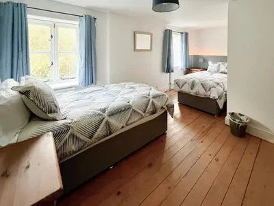 a bedroom with two beds and a window at Sandy Toes Cottage in Beechamwell
