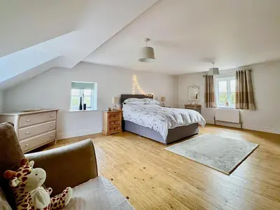 a bedroom with a bed and a chair in it at Sandy Toes Cottage in Beechamwell