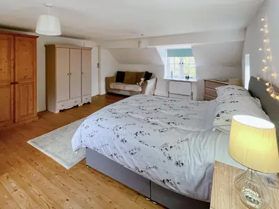 a bedroom with a large bed and a couch at Sandy Toes Cottage in Beechamwell