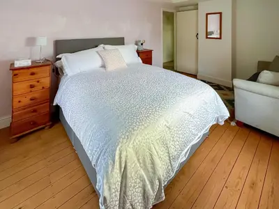 a bedroom with a bed and a dresser and a chair at Sandy Toes Cottage in Beechamwell