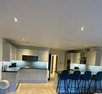 a kitchen with white cabinets and blue bar stools at Cosy nook in Hardwick