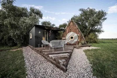 a small cabin with a table and chairs in front of it at Unique glamping experience near Ely & Cambridge in Ely