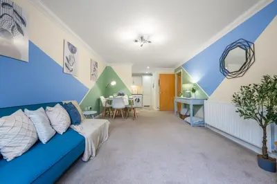 a living room with a blue couch and a table at STN - Bishops's Stortford - Free Gated Parking - Two Bed Apartment - Perfect location for Stansted Airport in Bishops Stortford