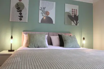 a bedroom with a bed with blue walls and two lamps at STN - Bishops's Stortford - Free Gated Parking - Two Bed Apartment - Perfect location for Stansted Airport in Bishops Stortford