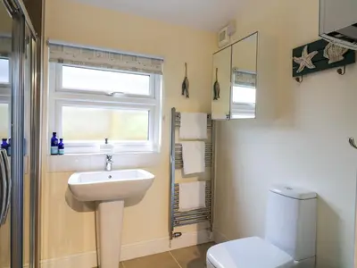 a bathroom with a sink and a toilet and a window at Compass Cottage in Aldeburgh