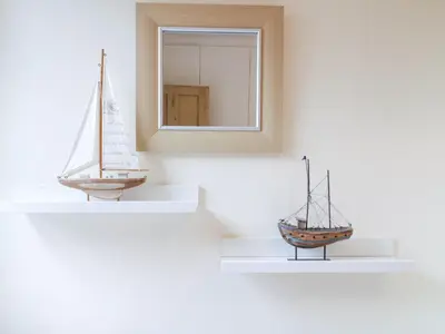 two models of boats are on shelves in a wall at Compass Cottage in Aldeburgh