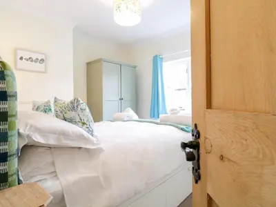 a bedroom with a white bed and a window at Compass Cottage in Aldeburgh