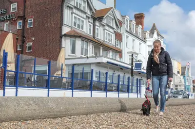 a woman walking a black dog on a leash at The Brudenell in Aldeburgh
