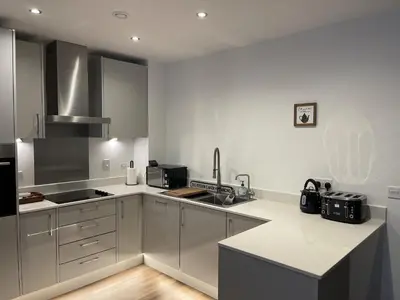 a kitchen with stainless steel appliances and white cabinets at The Melodies with Free Parking , Harlow in Harlow
