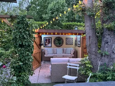 a patio with a couch and a table and a tree at River Mill Retreat in Little Hallingbury