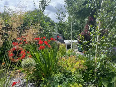 a garden with flowers and plants in front of a house at River Mill Retreat in Little Hallingbury