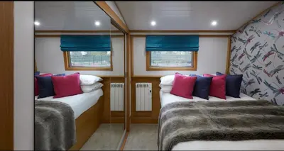 a small room with two beds with blue and red pillows at River Mill Retreat in Little Hallingbury