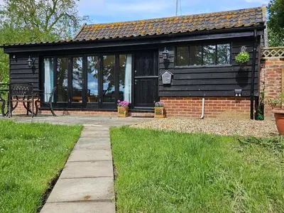 a black cottage with a picnic table in front of it at Lilys Cottage - Sleeps 2 - Pet friendly in Stowmarket