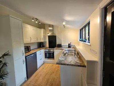 a kitchen with white cabinets and granite counter tops at Lilys Cottage - Sleeps 2 - Pet friendly in Stowmarket