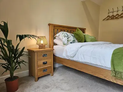 a bedroom with a bed and a night stand with a plant at Lilys Cottage - Sleeps 2 - Pet friendly in Stowmarket