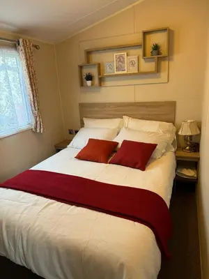 a bedroom with a large white bed with two red pillows at Modern & Blissful Beach Park Holiday Home in Dovercourt, Essex, in Parkeston