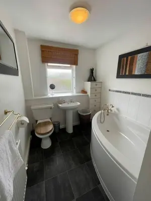 a bathroom with a tub and a toilet and a sink at Spacious House Near Cambridge - Free Parking and Garden in Cambridge