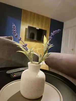 a white vase with purple flowers on a table at Sizewell - Contractors - Free Parking - Vacation in Leiston