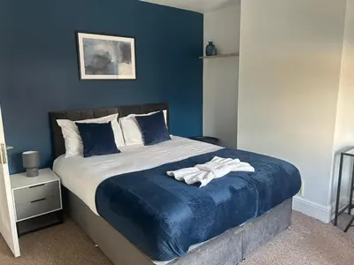 a bedroom with a large bed with blue walls at Sizewell - Contractors - Free Parking - Vacation in Leiston