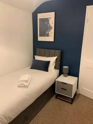 a bedroom with a bed with a blue wall at Sizewell - Contractors - Free Parking - Vacation in Leiston