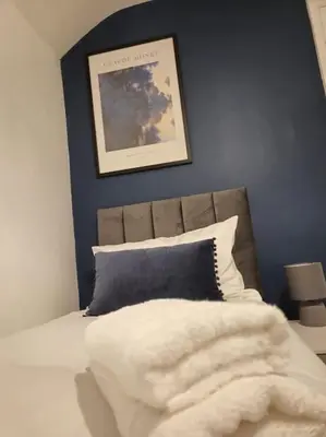 a bed with a white blanket and a blue wall at Sizewell - Contractors - Free Parking - Vacation in Leiston