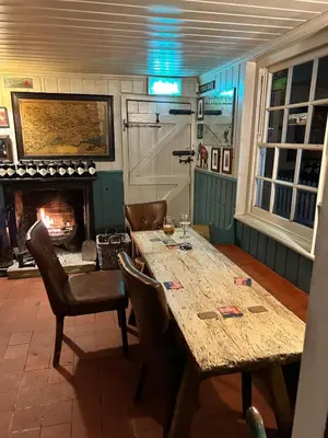 a dining room with a table and a fireplace at The Prince of Wales in Purleigh