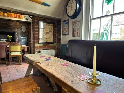 a wooden table in a restaurant with a clock on the wall at The Prince of Wales in Purleigh