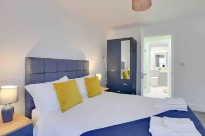 a bedroom with a large white bed with yellow pillows at Chelmer Springs Maisonettes in Chelmsford