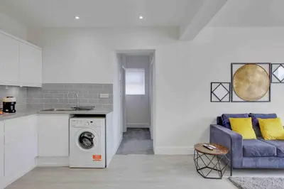 a kitchen with a washing machine and a blue couch at Chelmer Springs Maisonettes in Chelmsford