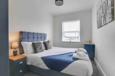 a bedroom with a blue and white bed and a window at Chelmer Springs Maisonettes in Chelmsford