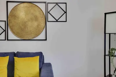 a living room with a blue couch and a gold plate on a wall at Chelmer Springs Maisonettes in Chelmsford