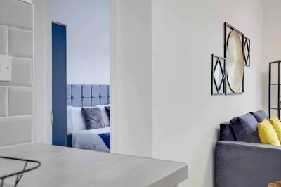 a living room with a blue couch and a mirror at Chelmer Springs Maisonettes in Chelmsford