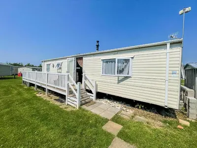 a white trailer with a porch and a fence at Caravan With Large Decking At Coopers Beach Holiday Park Ref 49036Ts in East Mersea
