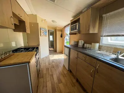 a kitchen with a sink and a stove top oven at Caravan With Large Decking At Coopers Beach Holiday Park Ref 49036Ts in East Mersea