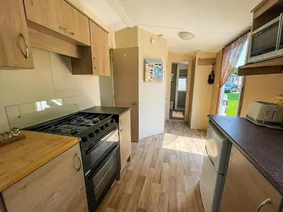 a kitchen with a stove and a counter top at Caravan With Large Decking At Coopers Beach Holiday Park Ref 49036Ts in East Mersea