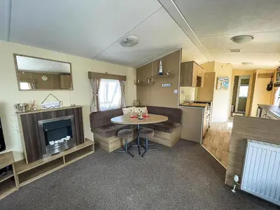a living room with a table and a kitchen at Caravan With Large Decking At Coopers Beach Holiday Park Ref 49036Ts in East Mersea
