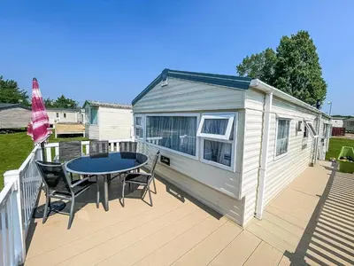a tiny house with a table and chairs on a deck at Caravan With Large Decking At Coopers Beach Holiday Park Ref 49036Ts in East Mersea
