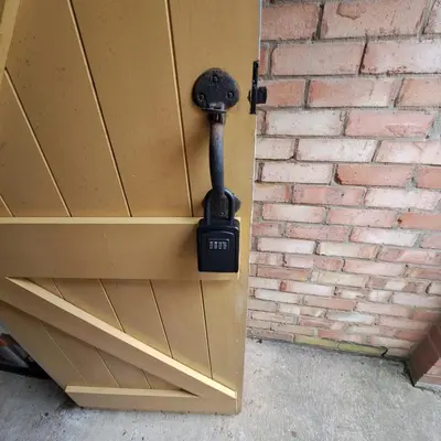 a wooden cabinet with a lock on a brick wall at Cute little 2 bed near Cambridge in Fenstanton