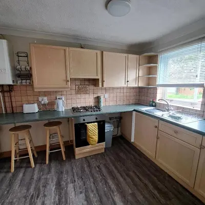a kitchen with wooden cabinets and a stove top oven at Cute little 2 bed near Cambridge in Fenstanton