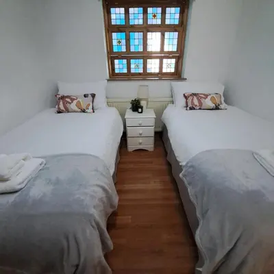 two twin beds in a room with a window at Cute little 2 bed near Cambridge in Fenstanton