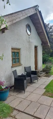 a house with chairs and a table and a window at Straw Bale Cottage in Halesworth