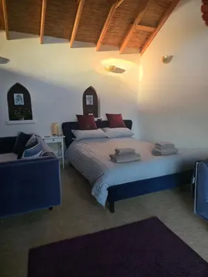 a bedroom with a bed and a couch at Straw Bale Cottage in Halesworth