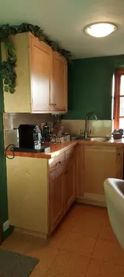 a kitchen with wooden cabinets and a sink at Straw Bale Cottage in Halesworth