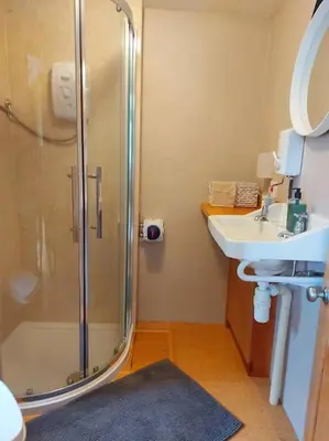 a bathroom with a shower and a sink at Straw Bale Cottage in Halesworth