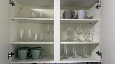 two shelves with wine glasses and cups on them at DK House in Colchester